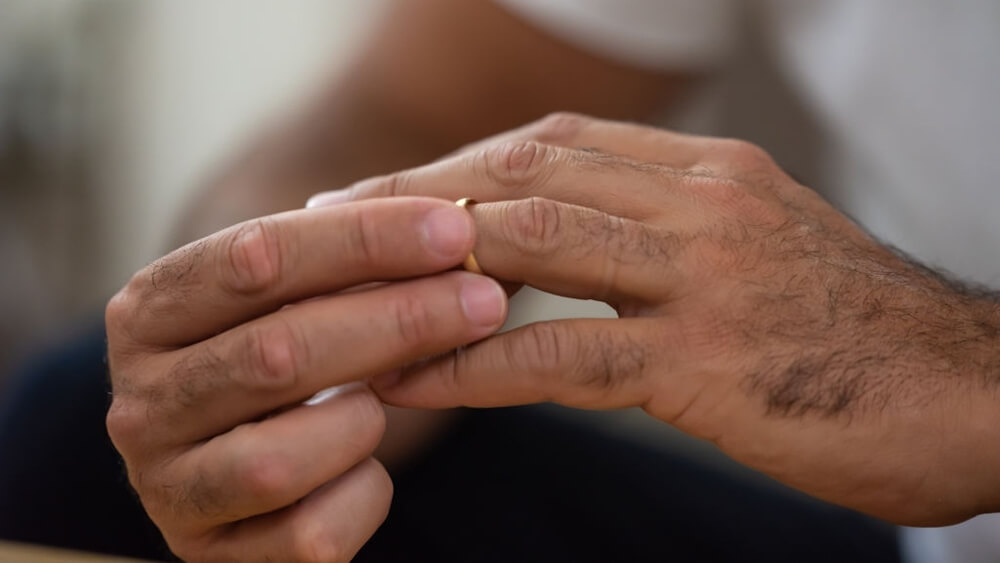 A man takes off his wedding band from his hand