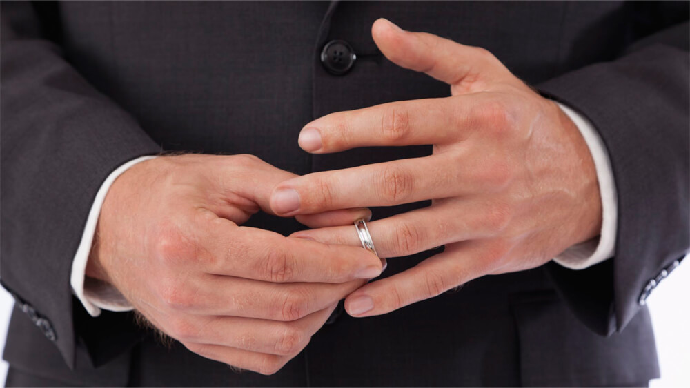 A man with suit removing his wedding ring