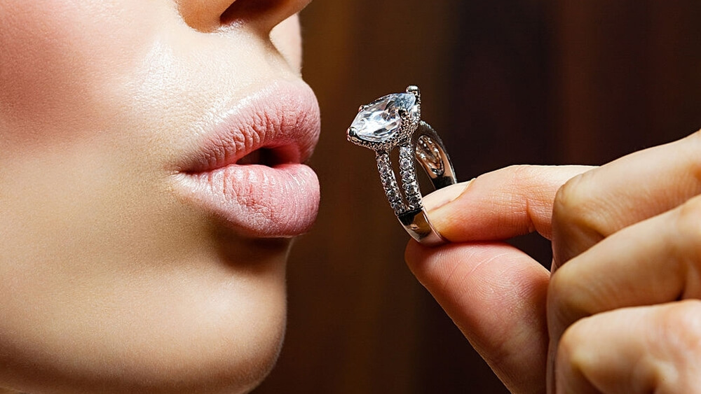 Young woman holding engagement ring with diamond