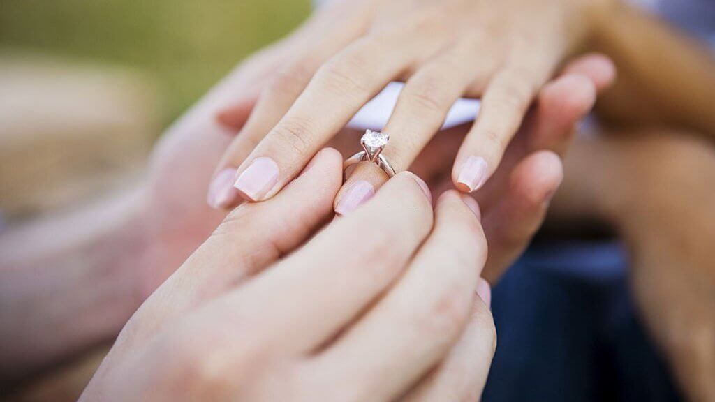 Female and male hands wearing engagement ring