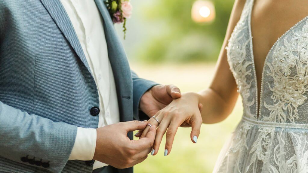 Man wearing wedding ring on woman's hand
