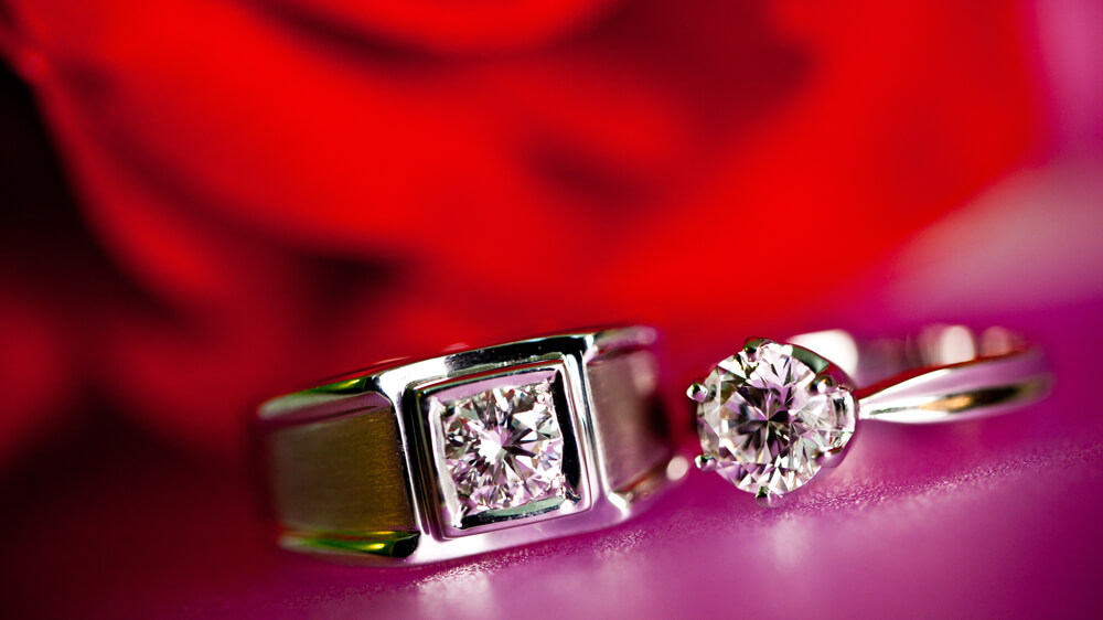 Couple diamond rings closeup on red background as the symbol of love