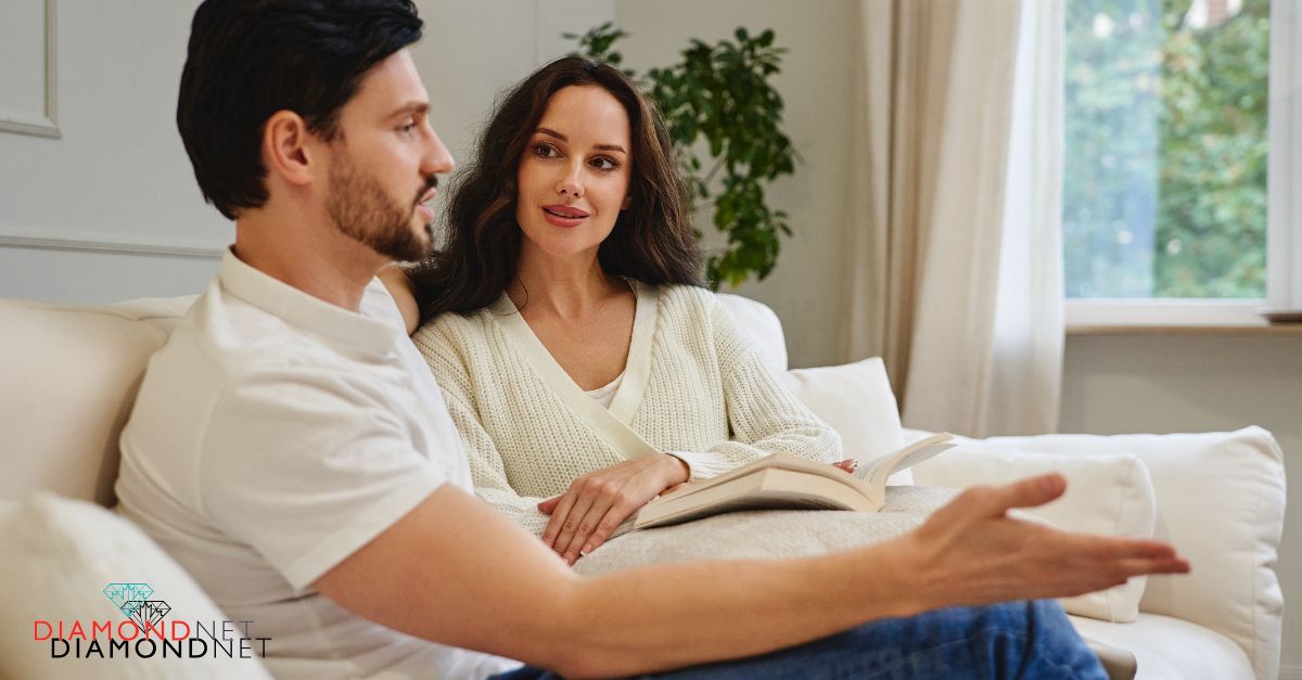 A young couple sits together on a couch in their living room, reflecting on relationship milestones before their engagement