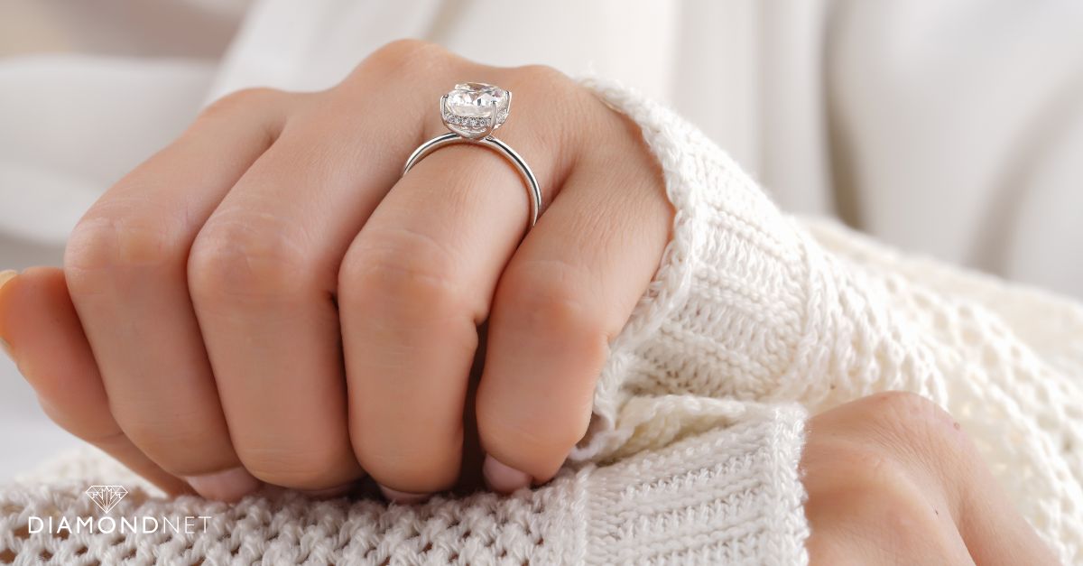 A woman's hand elegantly holds a diamond ring featuring a hidden halo setting