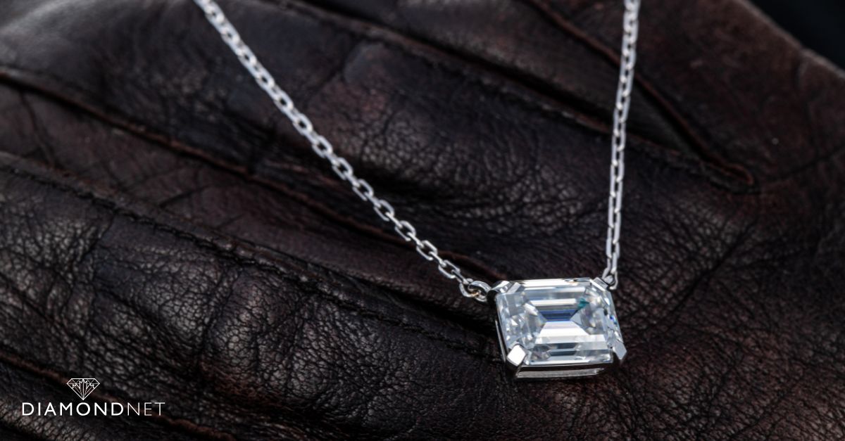 A delicate diamond pendant necklace displayed on a velvet stand